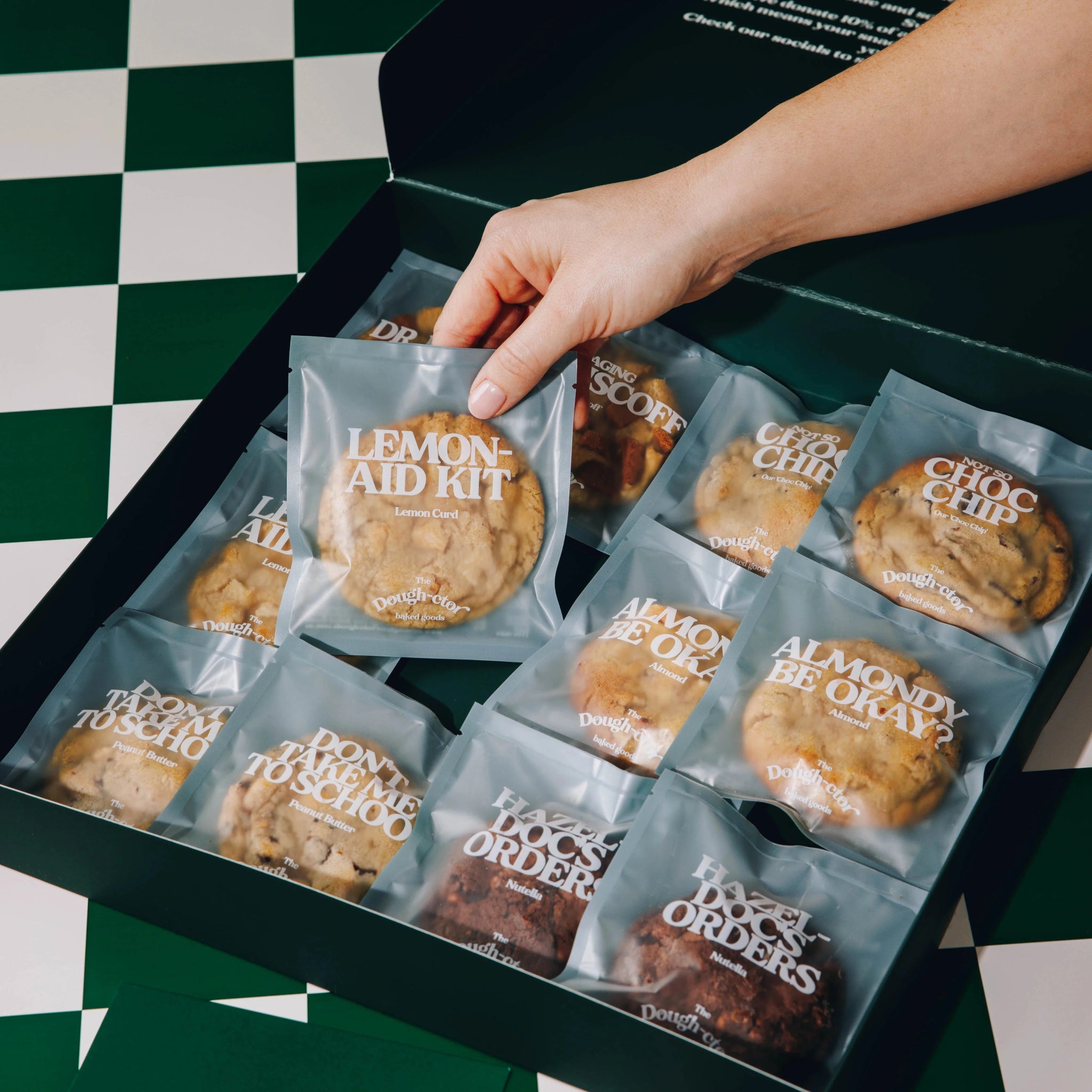Variety Pack - The Dough - ctor Baked Goods - 6 - pack variety - opened box - hand reaching grabbing a cookie - angled View